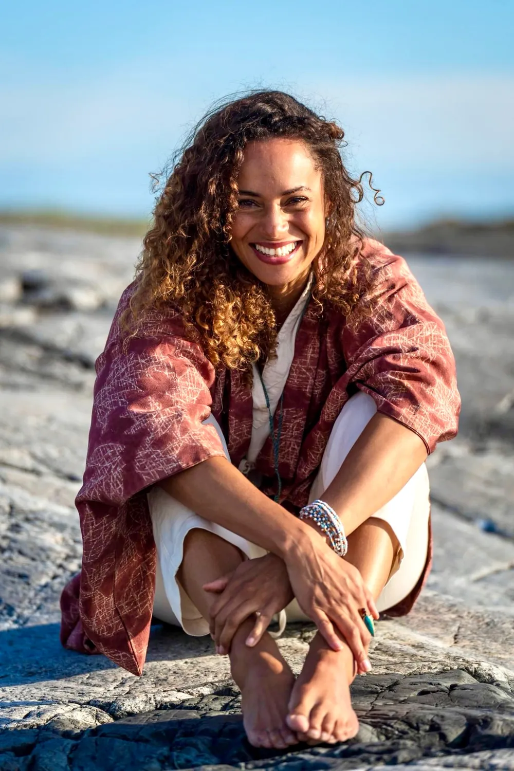 Charlene Edlund smiling on rocks by the sea